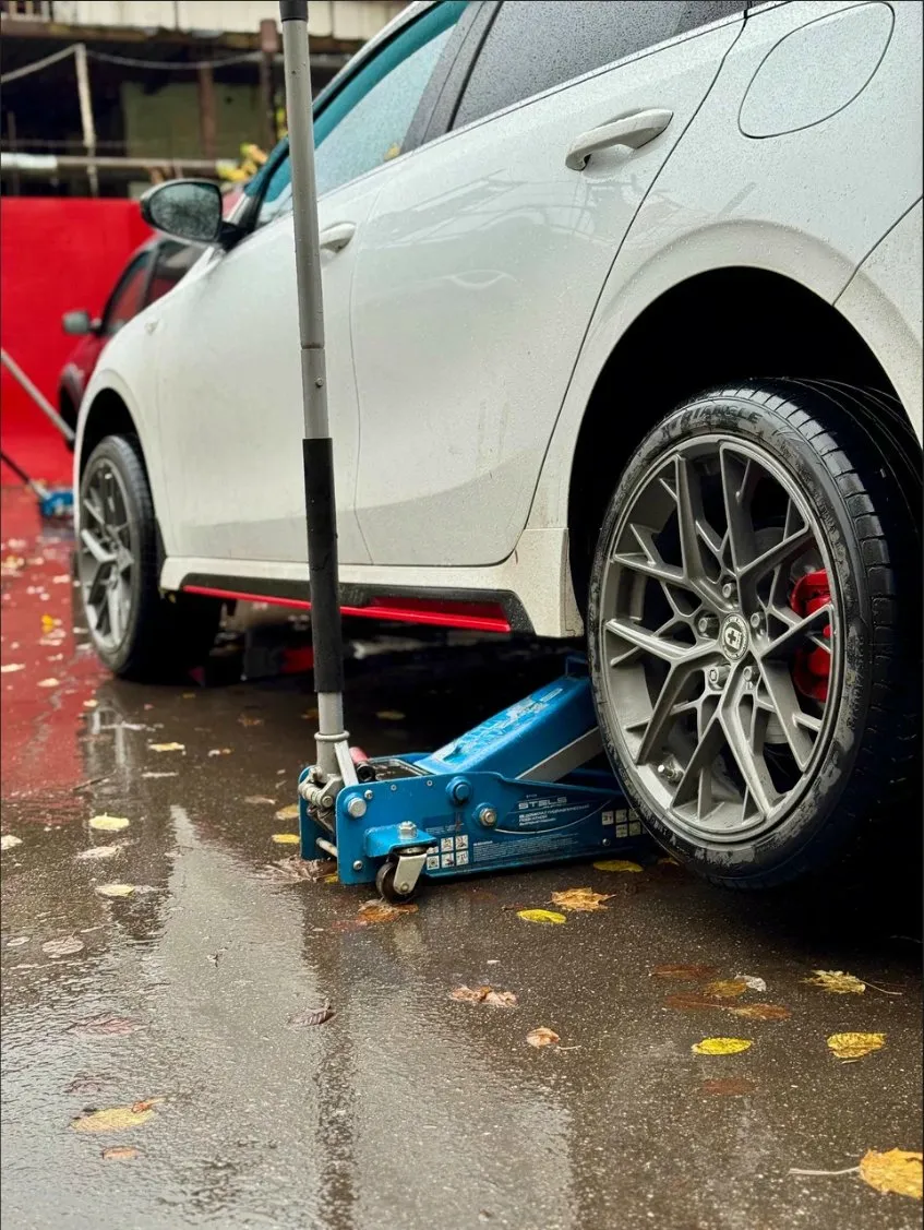 Белый хэтчбек в дождь, домкрат
