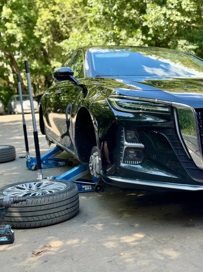 Тёмный седан Genesis, снятое колесо